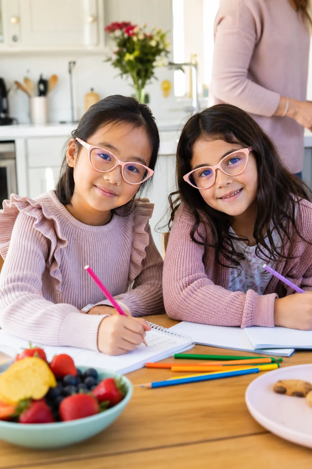 Twin girls with matching pink glasses doing homework
