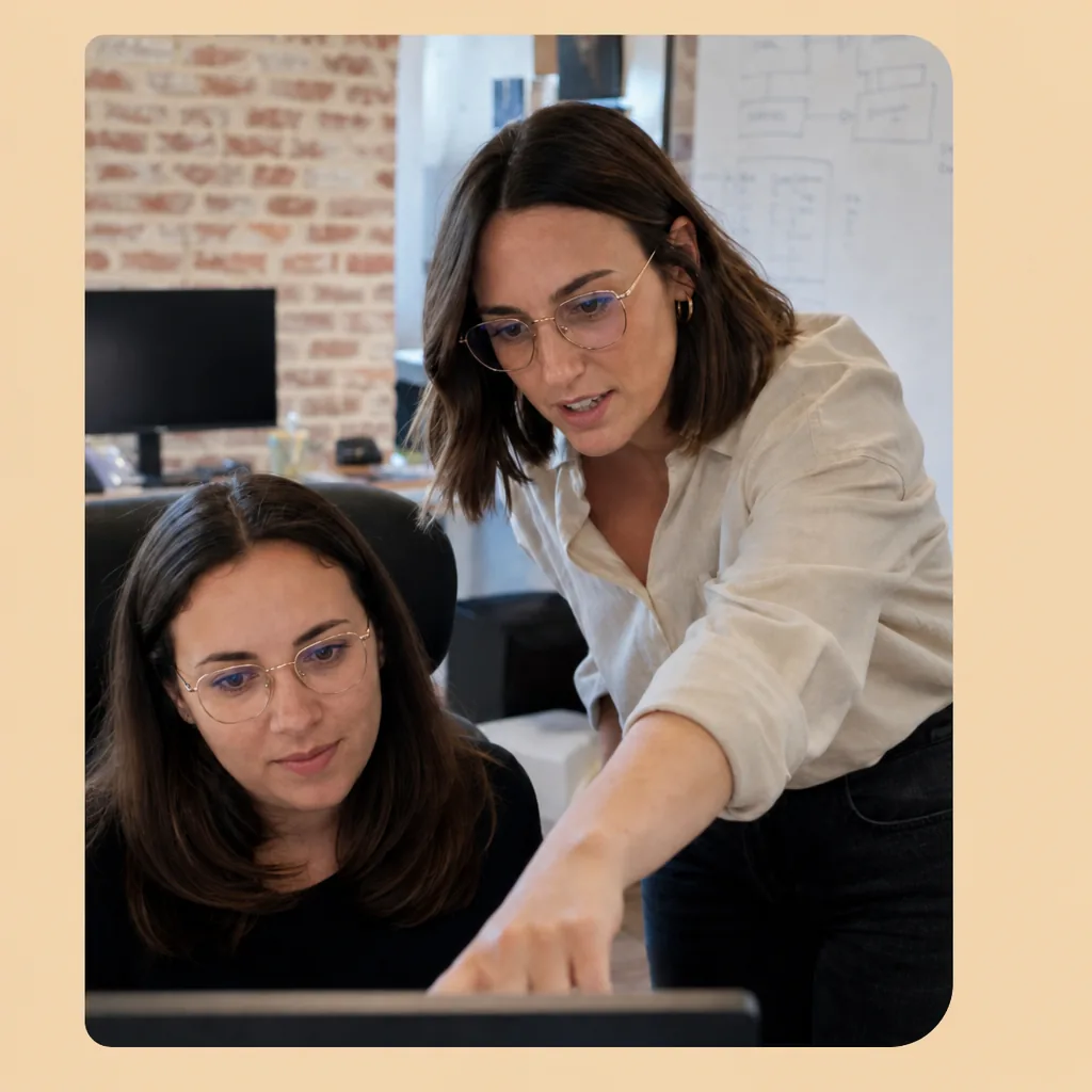 Female team leader reviewing monitor with colleague in gold-frame glasses